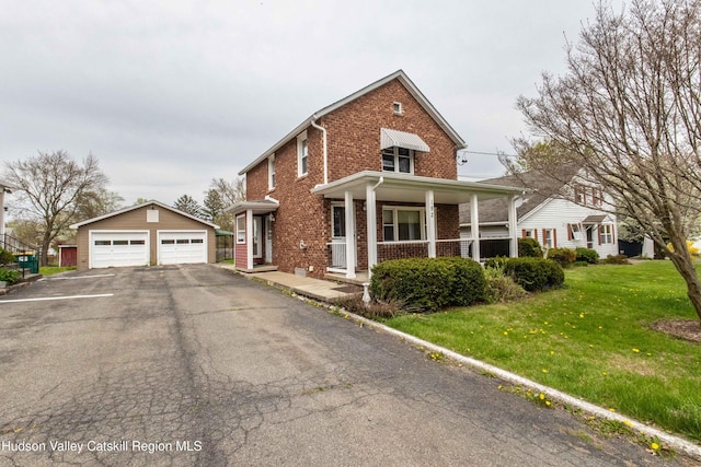 traditional-style home featuring an outdoor structure, a garage, a front lawn, brick siding, and a porch