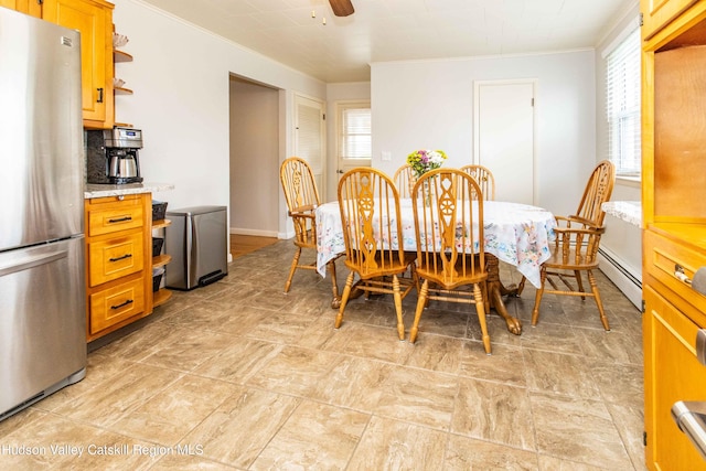 dining space featuring crown molding, plenty of natural light, and a baseboard heating unit