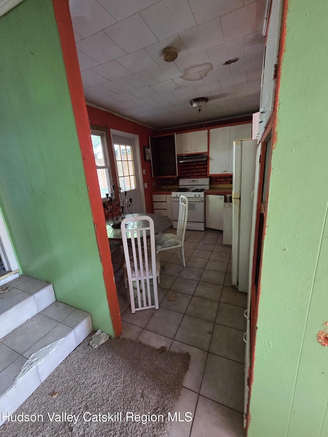 95 Spring St, Catskill, NY 12414 - kitchen with white appliances, light tile patterned flooring, white cabinetry, and under cabinet range hood