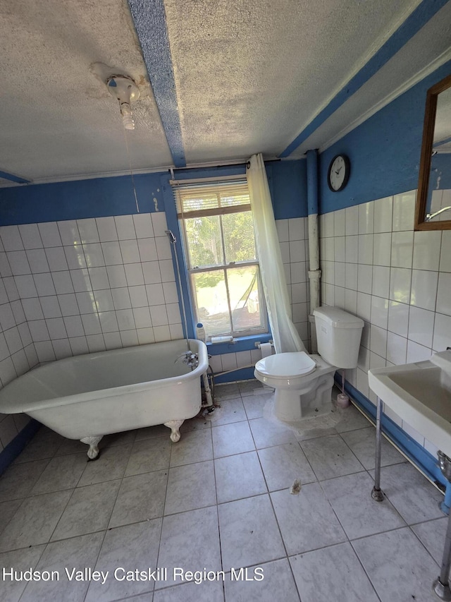 95 Spring St, Catskill, NY 12414 - full bathroom featuring a textured ceiling, a freestanding bath, tile walls, and tile patterned flooring