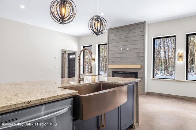 kitchen featuring stainless steel dishwasher, hanging light fixtures, concrete flooring, a wealth of natural light, and light stone counters