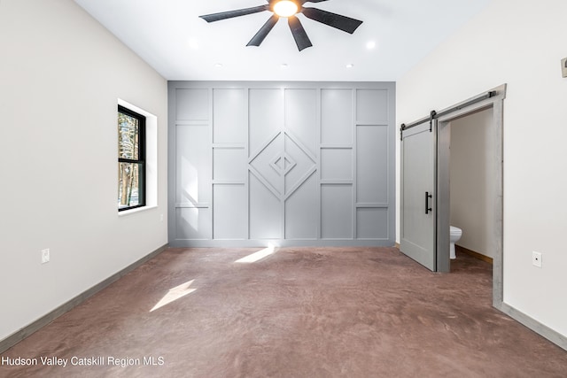 unfurnished bedroom featuring ensuite bathroom, ceiling fan, and a barn door