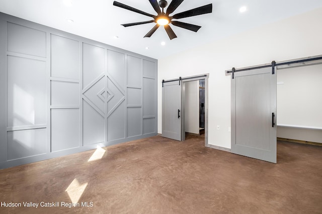 unfurnished bedroom with ceiling fan, a barn door, and carpet floors