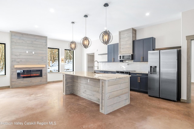 kitchen with tasteful backsplash, pendant lighting, stainless steel appliances, light stone counters, and a center island with sink