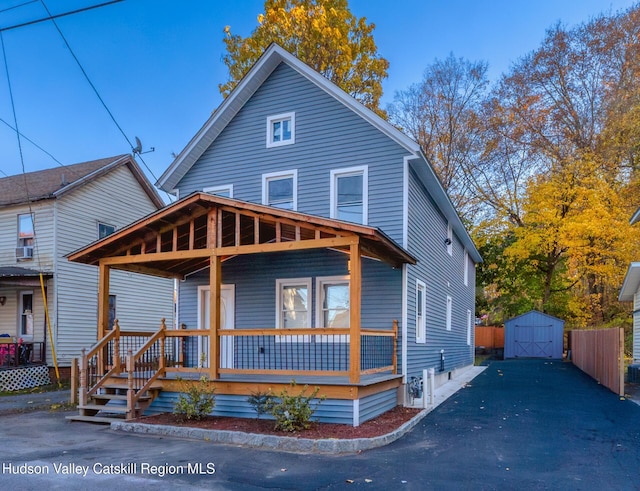 view of front of home featuring covered porch and a storage shed