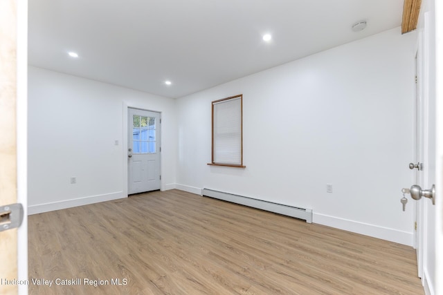 empty room with light hardwood / wood-style flooring and baseboard heating