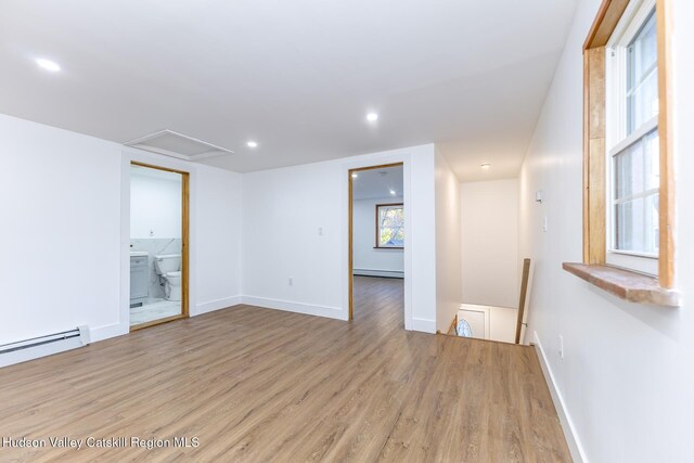 unfurnished room with a baseboard heating unit and light hardwood / wood-style flooring