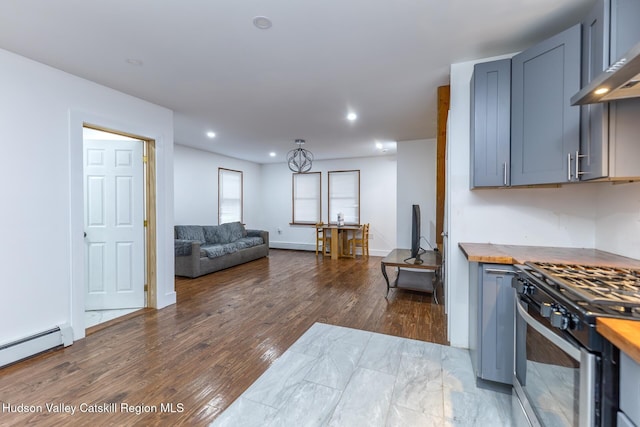 kitchen with dark hardwood / wood-style flooring, wall chimney exhaust hood, a baseboard heating unit, butcher block counters, and stainless steel range with gas stovetop