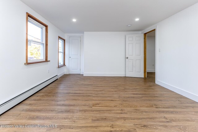 unfurnished room with light hardwood / wood-style floors and a baseboard radiator