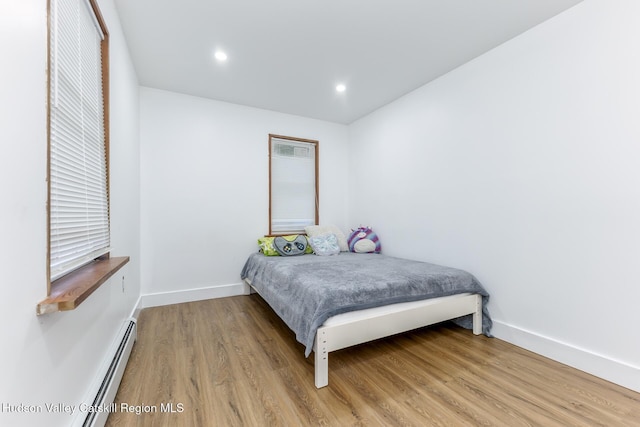 bedroom featuring hardwood / wood-style flooring and a baseboard heating unit