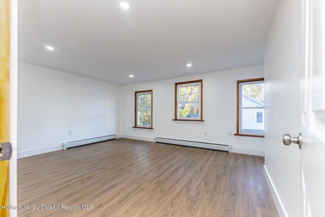 empty room featuring a baseboard radiator and hardwood / wood-style flooring