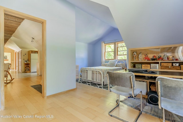 bedroom with white fridge, lofted ceiling, and light hardwood / wood-style floors