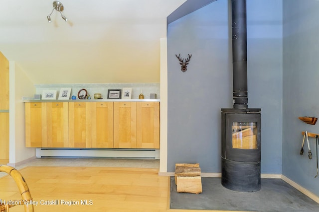 room details featuring hardwood / wood-style flooring, a wood stove, and a baseboard heating unit