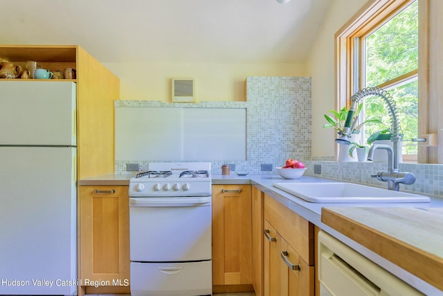 kitchen with decorative backsplash, white appliances, and sink