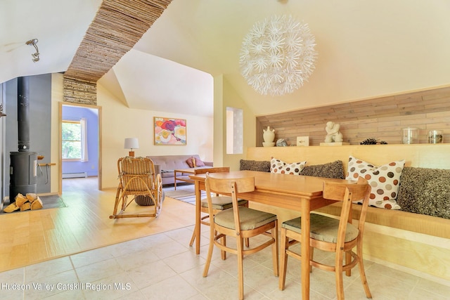 dining space with lofted ceiling, wood-type flooring, baseboard heating, and an inviting chandelier