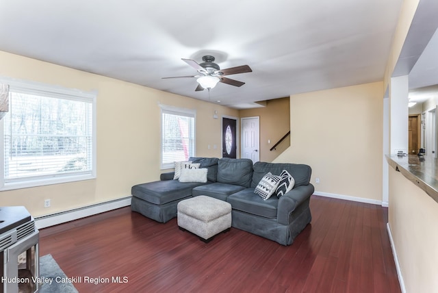 living area with ceiling fan, baseboard heating, dark wood finished floors, and baseboards