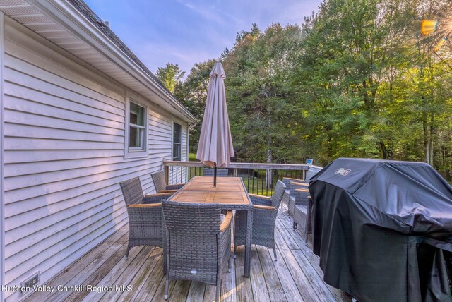 wooden deck with outdoor dining area and grilling area