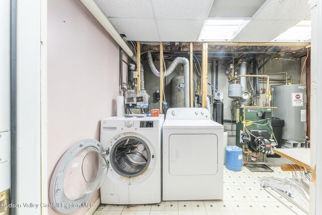 washroom with washer and clothes dryer, a heating unit, electric water heater, laundry area, and tile patterned floors