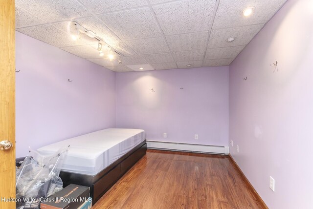 bedroom featuring baseboard heating, ceiling fan, and dark hardwood / wood-style floors