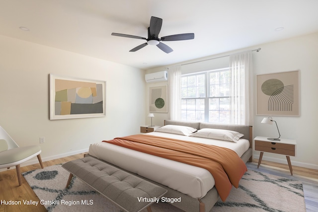 bedroom with light wood-style floors, a wall mounted air conditioner, ceiling fan, and baseboards