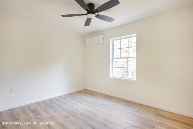 empty room with light wood-style floors, an AC wall unit, and baseboards