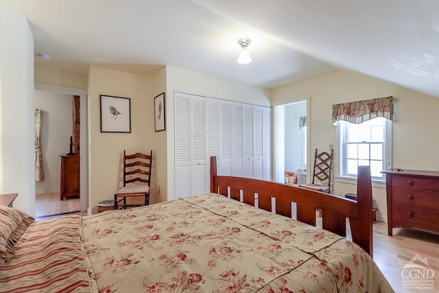 bedroom with light wood finished floors, a closet, and lofted ceiling