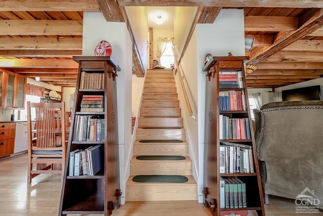 stairway with wood finished floors and beam ceiling