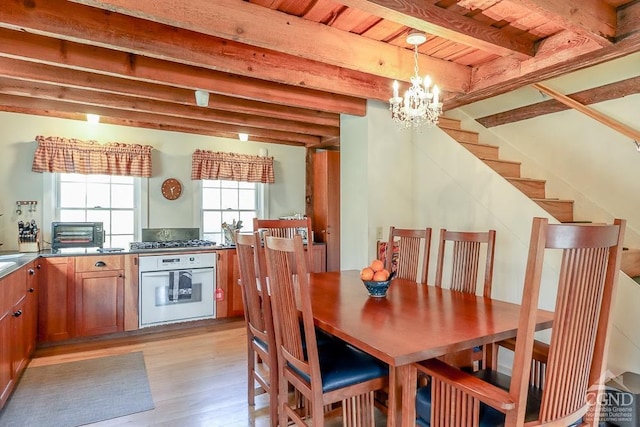dining space featuring light wood finished floors, a chandelier, beam ceiling, stairs, and wooden ceiling