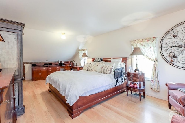 bedroom with light wood-type flooring and lofted ceiling