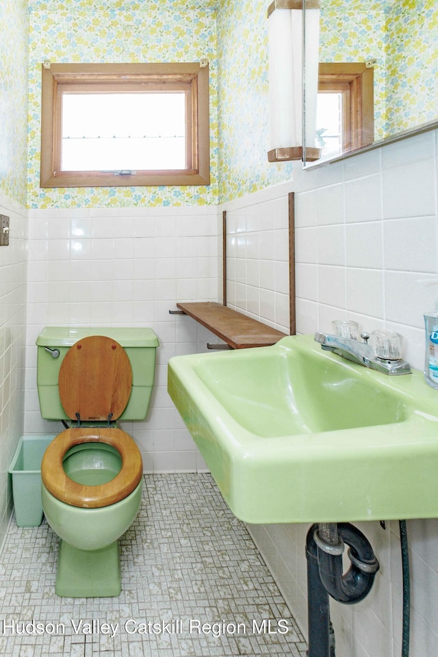 bathroom featuring a wainscoted wall, plenty of natural light, and wallpapered walls