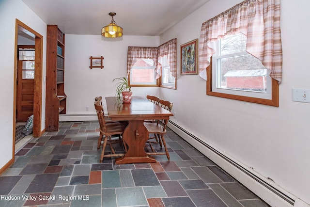 unfurnished dining area featuring a baseboard radiator, stone finish floor, and baseboards