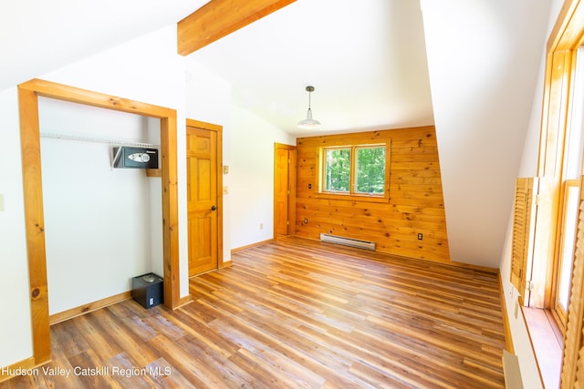 unfurnished bedroom featuring baseboard heating, lofted ceiling with beams, wood walls, wood-type flooring, and a closet