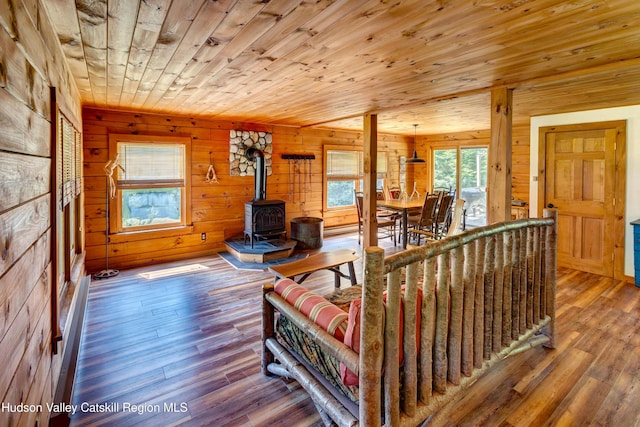 living room with hardwood / wood-style flooring, a wood stove, wooden walls, and wooden ceiling