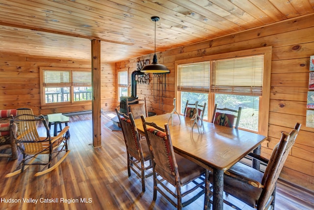 dining area featuring wooden walls, a healthy amount of sunlight, and dark hardwood / wood-style floors