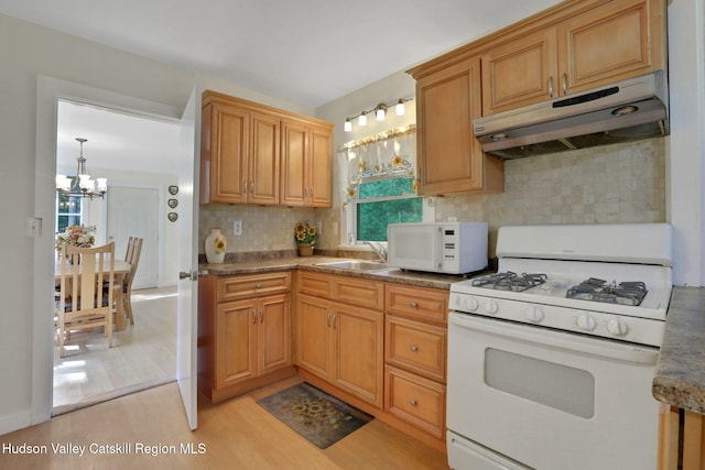 1055 Rte 212, Saugerties, NY 12477 - kitchen with white appliances, under cabinet range hood, a chandelier, backsplash, and light wood-type flooring