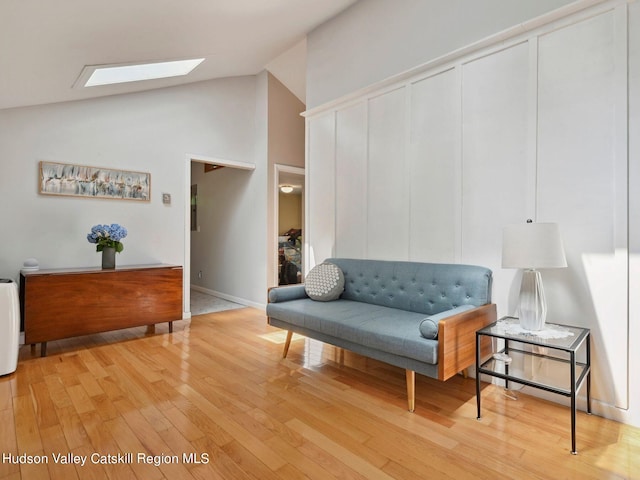 interior space featuring a skylight, high vaulted ceiling, and light hardwood / wood-style floors