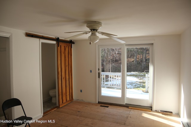 doorway to outside featuring ceiling fan, a barn door, and light hardwood / wood-style flooring