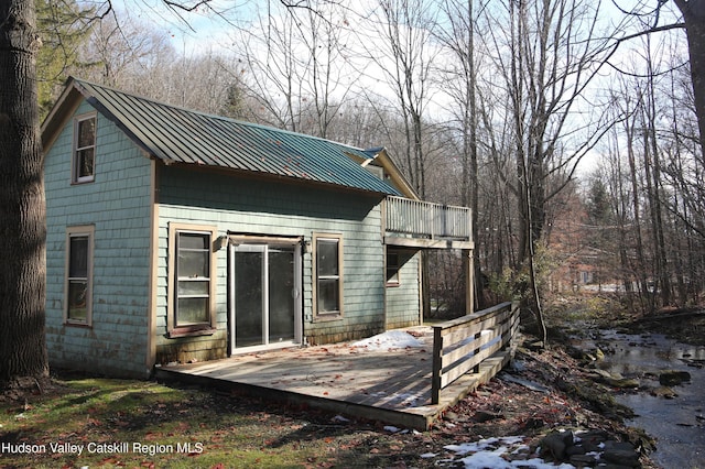 rear view of property with a balcony and a wooden deck