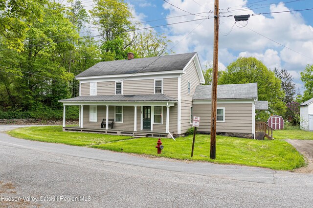 1 Green St, Gilbertsville, NY 13776 - view of front of home featuring a storage shed, a porch, a chimney, an outdoor structure, and a front yard