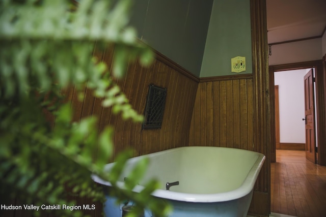 121 Birch Creek Rd, Pine Hill, NY 12465 - bathroom featuring a freestanding tub, wooden walls, wainscoting, and hardwood / wood-style flooring