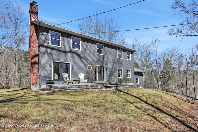 rear view of house featuring a lawn and a chimney