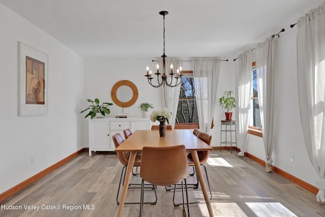 dining space with an inviting chandelier, baseboards, and light wood finished floors