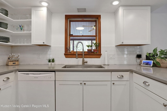 kitchen featuring light countertops, decorative backsplash, a sink, white cabinets, and white dishwasher