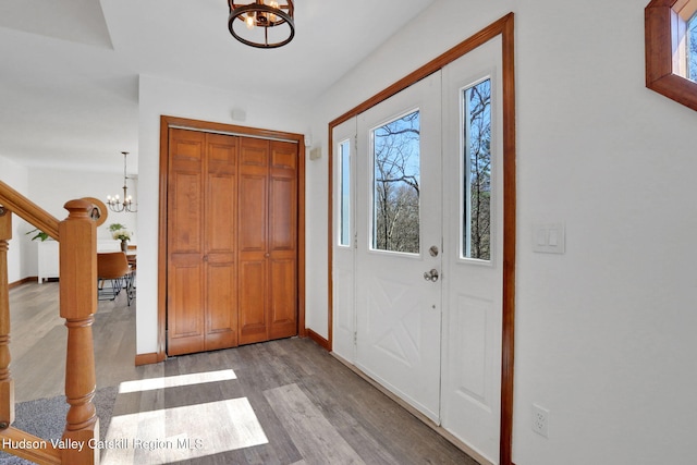 foyer entrance with a notable chandelier, baseboards, light wood-style floors, and stairs