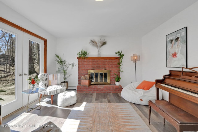 living room with a fireplace, french doors, a baseboard heating unit, and wood finished floors