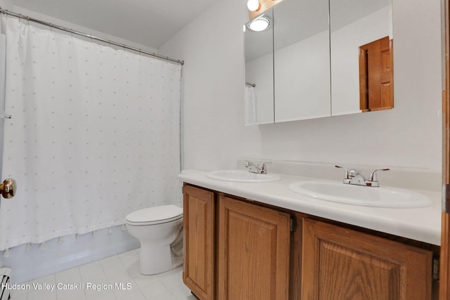 full bathroom with double vanity, a sink, toilet, and a baseboard heating unit