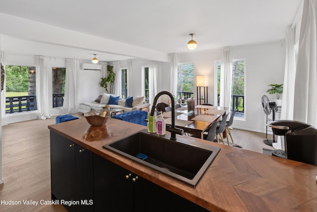 2064 County Highway 8, Denver, NY 12421 - kitchen featuring wooden counters, dark cabinets, open floor plan, light wood finished floors, and a wall mounted air conditioner