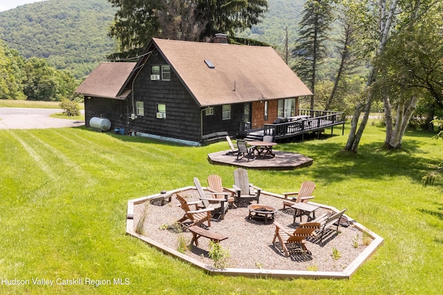 2064 County Highway 8, Denver, NY 12421 - rear view of property featuring an outdoor fire pit, a deck with mountain view, a chimney, a yard, and a wooded view