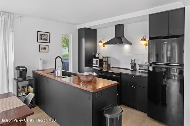 2064 County Highway 8, Denver, NY 12421 - kitchen with wall chimney range hood, freestanding refrigerator, backsplash, light wood-style flooring, and dark cabinetry