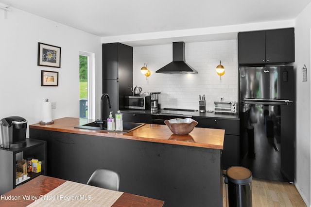 2064 County Highway 8, Denver, NY 12421 - kitchen with freestanding refrigerator, wall chimney exhaust hood, butcher block countertops, stainless steel microwave, and a breakfast bar